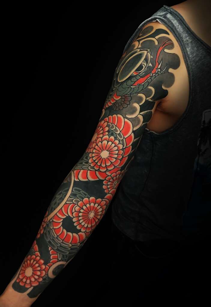 Tatouage d'une manchette complète (Nagasode) représentant un serpent et des chrysanthèmes (Kiku) dans un style Irezumi revisité, réalisé en Alsace au studio Nuevo Mundo proche de la frontière Suisse.